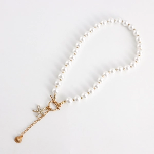Detailed macro of ocean theme pearl necklace featuring starfish pendant and shell charm