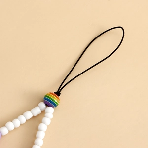 Détail de perles blanches artisanales avec accent arc-en-ciel sur cordon de téléphone