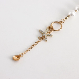 Macro detail of starfish pendant with rhinestones and white shell beads necklace