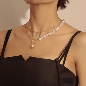 Dettaglio collana a doppio strato dorata con perla barocca e pendenti geometrici