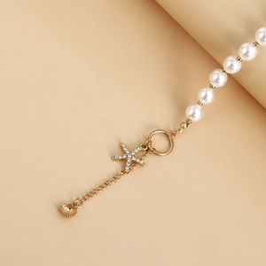 Close-up of pearl necklace featuring a rhinestone starfish charm and small golden shell