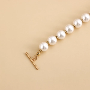 Detail shot of the golden OT toggle clasp on a shell and pearl beaded necklace
