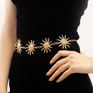 Detail of a golden metal chain belt featuring sun face charms on a black dress