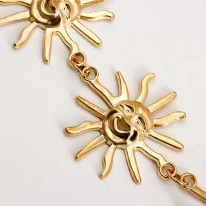 Close-up of golden sun face links on a polished metal chain belt for women's dresses