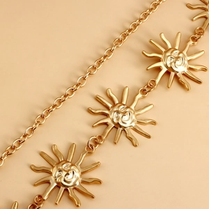 Close-up of golden metal waist chain featuring sun face pendants and link chain