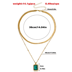 Double-layered gold snake chain necklace with a green gemstone pendant and crystal border