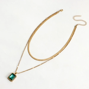 Detailed view of gold double-layer snake chain necklace with emerald pendant and tiny diamonds