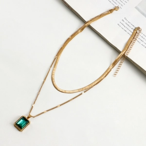 Detail of gold snake chain with double layers and a green gemstone rectangle pendant