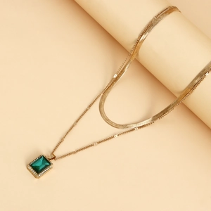 Detail of double-layer gold snake chain necklace with rectangular emerald pendant