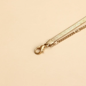 Detail of gold double-layer necklace with flat snake chain and lobster clasp closure