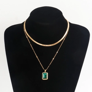 Detail of double-layer golden snake chain and rectangular emerald faux gemstone pendant