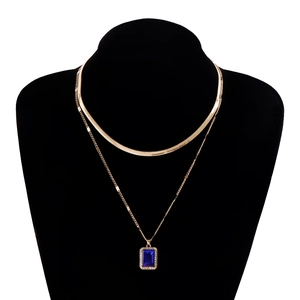 Close-up of double-layered gold snake chain featuring a rectangular blue gemstone pendant