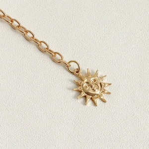 Detailed macro view of a golden sun face pendant on a polished link chain jewelry piece