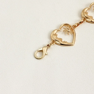 Detailed macro view of golden heart-shaped charms with sun and moon relief on metal belt
