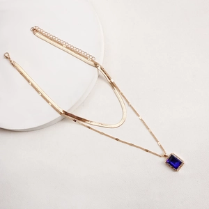 Detail of double-layer gold snake chain featuring a rectangular blue gemstone pendant