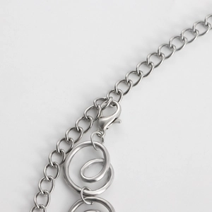 Detail of silver spiral geometric waist chain with lobster clasp and polished finish
