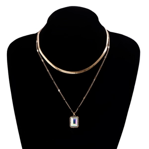 Detail of double-layer gold snake chain featuring a rectangular iridescent gemstone pendant