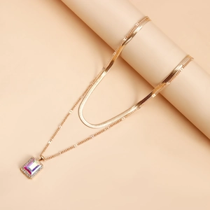 Detailed view of golden double-layer necklace with flat snake chain and gemstone pendant