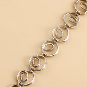 Elegant silver spiral geometric metal waist chain with circular rings on a beige background