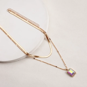 Detail of double-layer gold snake chain necklace with a colorful gemstone pendant