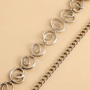 Macro detail showing the intertwined silver spiral rings and fine metal chain link texture