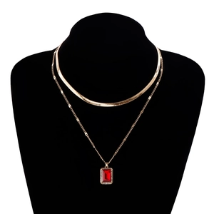 Detailed macro view of gold layered snake chain and ruby pendant with crystal accents