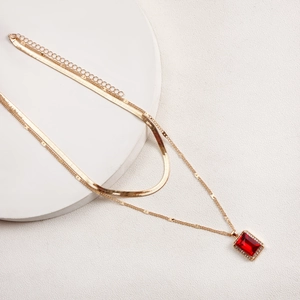 Detail of double-layer golden snake chain featuring a rectangular red gemstone pendant