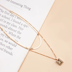 Close-up of double-layered gold snake chain necklace with champagne gemstone pendant