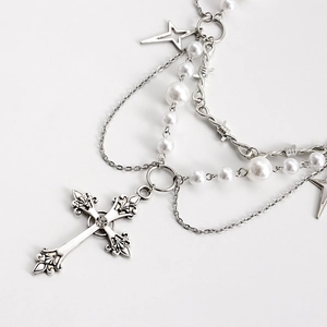 Detailed macro view of layered necklace with cross pendant, pearls and star charms