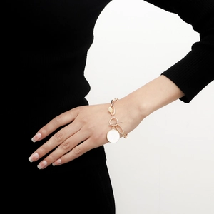 Detailansicht eines Goldkettenarmbands mit weißem Muschel-Anhänger und OT-Verschluss