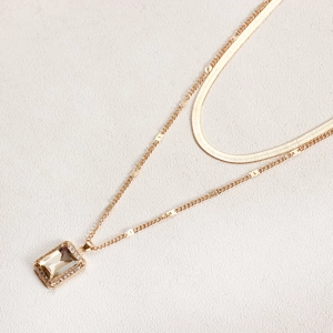 Detailed macro of a double-layered gold snake chain with a rectangular faux gemstone pendant