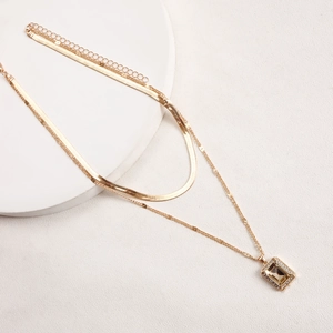 Detailed close-up of double-layered gold snake chain necklace with champagne gemstone pendant