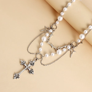 Detailed macro view of the double-layered pearl necklace with a vintage star and cross pendant