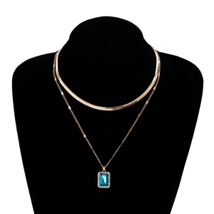 Detail of double-layer golden snake chain necklace with rectangular blue gemstone pendant