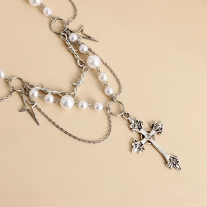 Detail of layered pearl necklace with engraved silver cross and star pendants