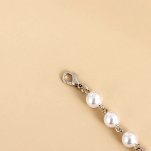 Detailed close-up of the silver lobster clasp and high-luster white pearls necklace