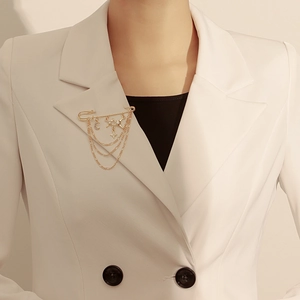 Détail d'une broche vintage étoile et lune à pompons sur un blazer blanc