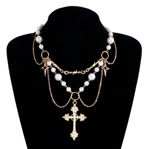Detail of layered gold necklace with pearls, cross pendant and star charms