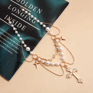 Detail of double-layer necklace featuring white pearls, gold stars, and a cross pendant