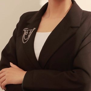 Detalle de broche de cadena multicapa plateado con colgante de corazón en traje negro