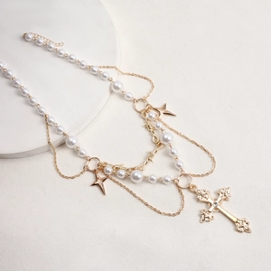 Detail of layered gold necklace with white pearls, star charms and hollow cross pendant