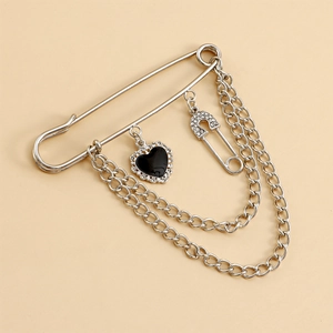 Detalle del broche de imperdible plateado con doble cadena y colgante de corazón