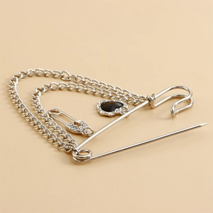 Detalle del broche de cadena plateada con colgante de corazón negro y diamantes