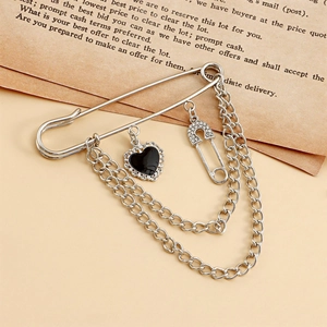 Detalle del broche de cadena plateada con corazón negro y colgante de mini pasador