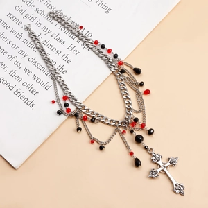 Detail of multilayer silver chain necklace with red beads and gothic cross pendant