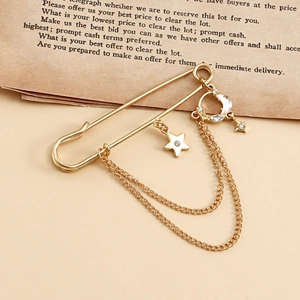 Détails d'une broche dorée avec étoile, lune et pampilles en cristal sur papier vintage