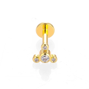 Détail d'un piercing labret en acier 316L doré avec grappe de fleurs en cristaux