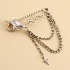 Détail d'une broche épingle argentée avec breloques étoiles et glands en cristal chic