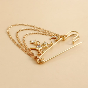 Détail d'une broche dorée à pampilles avec chaînes et pendentifs lune et étoiles sertis