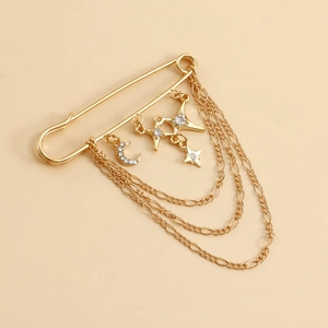 Détails d'une broche vintage dorée avec pompons étoile et lune et strass brillants